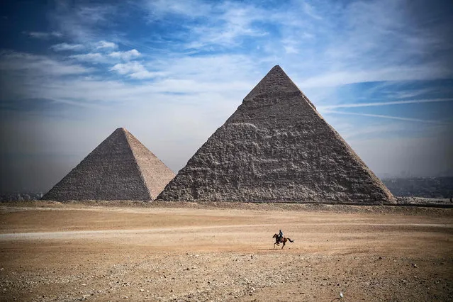 A man rides a horse in front of the pyramids of Khufu (Cheops) (L), Khafre (Chephren), at the Giza pyramids necropolis on the southwestern outskirts of the Egyptian capital Cairo, on January 26, 2021. (Photo by Anne-Christine Poujoulat/AFP Photo)