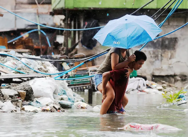 A resident carries a woman on his back along a flooded street caused by monsoon rains and Tropical Storm Son-Tinh in Quezon city, Metro Manila, Philippines on July 17, 2018. (Photo by Erik De Castro/Reuters)
