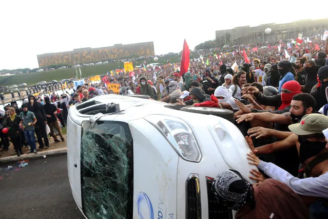 Anti-government demonstrators attack a press car of Tv Record as they attend a demonstration against a constitutional amendment, known as PEC 55, that limits public spending, in front of Brazil's National Congress in Brasilia, Brazil November 29, 2016. (Photo by Adriano Machado/Reuters)