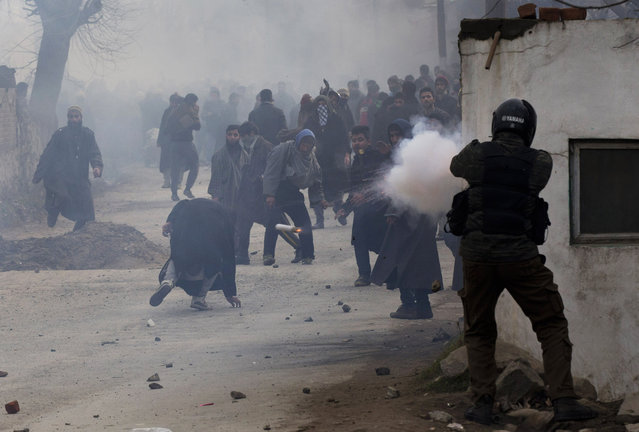 An Indian policeman fires a teargas shell as a Kashmiri Muslim, center, ducks to avoid it during the funeral procession of Sajad Ahmed Bhat, a top rebel commander on the outskirts of Srinagar, Indian controlled Kashmir, Tuesday, January 12, 2016. Clashes erupted in Indian-controlled Kashmir Tuesday as police fired tear gas to stop a march by thousands of people participating in a funeral procession of a local militant killed in a gunfight with government forces. (Photo by Dar Yasin/AP Photo)