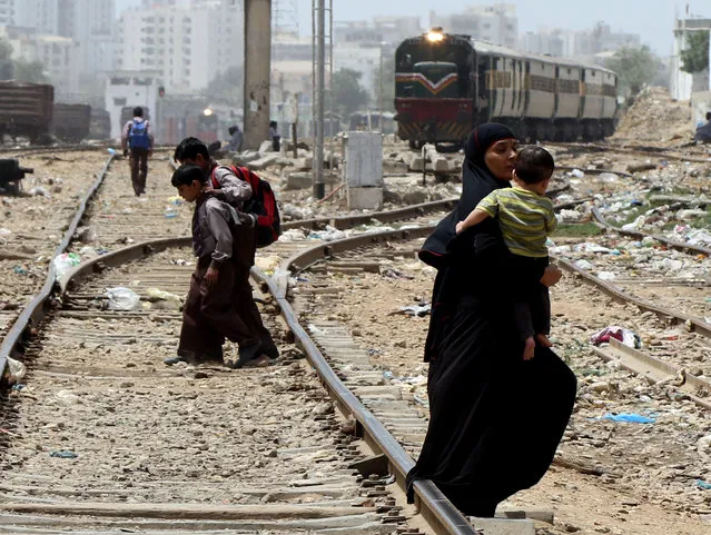 People cross the rail tracks without taking any precautions as a Goods train arrive in Karachi, Pakistan, 29 August 2018. Every year hundreds of people are killed or injured after hitting by trains in Pakistan. (Photo by Rehan Khan/EPA/EFE)