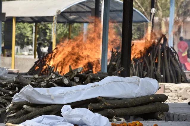The body of a person who died of Covid-19 is placed on a pyre while others burn in the background at Sector 94, on April 21, 2021 in Noida, India. (Photo by Sunil Ghosh/Hindustan Times via Getty Images)