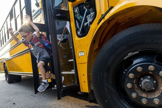Kindergartener Jaxon Schofield-Wood leaps off the bus excited for his first day of school on Monday, August 21, 2023, at Thomson Elementary School in Davison, Mich. (Photo by Jake May/The Flint Journal via AP Photo)