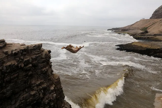 Fernando Jesus Canchari, dressed as a friar jumps from a 13-meter high cliff along Herradura Beach in Lima, December 7, 2016. (Photo by Guadalupe Pardo/Reuters)