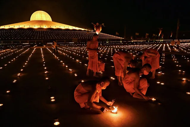 Buddhist monks light 330,000 candles in an attempt to break the Guinness World Record for the largest flaming image during Earth Day celebrations at the Wat Dhammakaya Buddhist temple on the outskirts of Bangkok on April 22, 2021. (Photo by Lillian Suwanrumpha/AFP Photo)