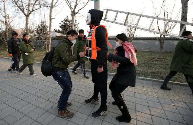 Assistants set up 24 mobile phones on artist Liu Bolin's vest before he live broadcasts air pollution in the city on the fourth day after a red alert was issued for heavy air pollution in Beijing, China, December 19, 2016. (Photo by Jason Lee/Reuters)