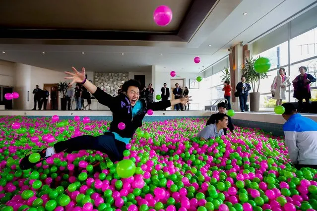 A man jumps in a swimming pool filled with pink and green plastic balls during a Guinness World Records attempt of the Largest Ball Pit as part of the “Pink October” campaign at Kerry Hotel in Pudong, Shanghai, on Oktober 30, 2013. The event, aimed at raising awareness of breast cancer prevention, set the world record with one million balls in the 82 by 41 foot swimming pool. (Photo by Aly Song/Reuters)