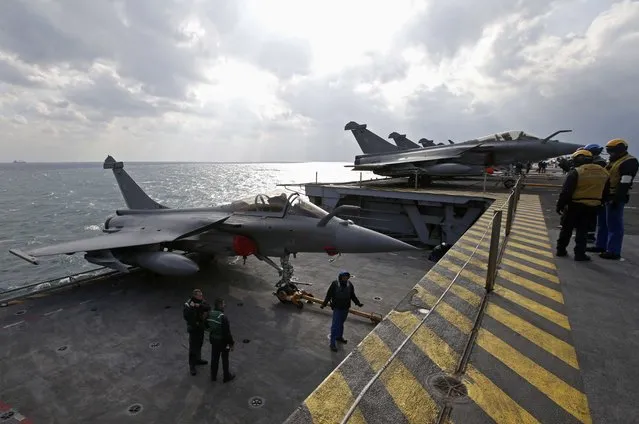 “Yellow dogs” fly deck directors watch as a Rafale fighter jet is brought up on an elevator to the flight deck aboard France's Charles de Gaulle aircraft carrier in the Gulf, January 29, 2016. (Photo by Philippe Wojazer/Reuters)