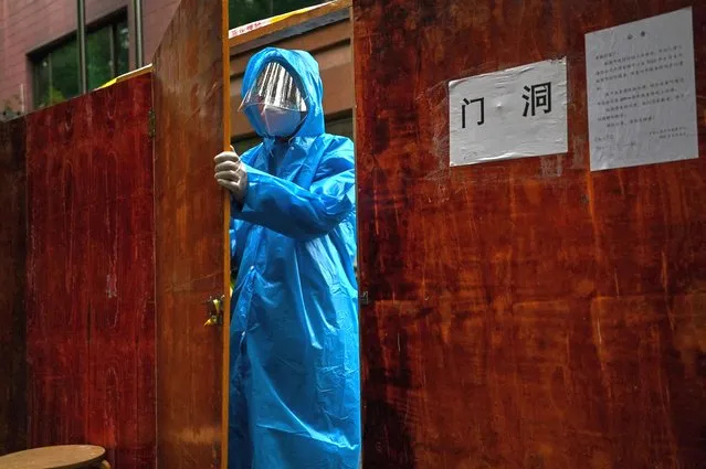 A worker prepares a fence to close a residential area under Covid-19 lockdown in the Huangpu district of Shanghai on June 10, 2022. (Photo by Hector Retamal/AFP Photo)
