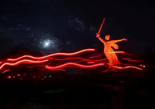 People carry candles past the “The Motherland Calls” monument illuminated in red during a ceremony to mark the 80th anniversary of German invasion into Soviet Union at the Mamayev Kurgan World War Two memorial complex in Volgograd, Russia June 21, 2021. Picture taken with slow shutter speed. (Photo by Kirill Braga/Reuters)