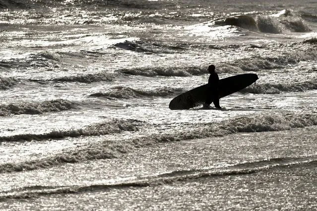 A man  carries a surfboard at Sandy Bay in Porthcawl, Wales, Tuesday, September 26, 2023. Strong winds and heavy rain are set to batter the UK as Storm Agnes sweeps across the country. Agnes, the first named storm of the season, will affect western regions of the UK and Ireland on Wednesday, with the most powerful winds expected on the Irish Sea coasts. (Photo by Joe Giddens/PA Wire via AP Photo)