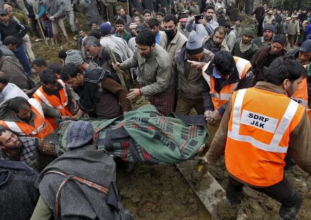 Villagers and rescue workers carry the body of a victim amongst the rubble after a hillside collapsed onto a house at Laden village, west of Srinagar, March 30, 2015. (Photo by Danish Ismail/Reuters)