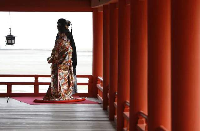 A bride in traditional Japanese wedding attire poses for photos with her groom at the Itsukushima Shrine in Hatsukaichi, southwestern Japan April 16, 2008. (Photo by Toru Hanai/Reuters)
