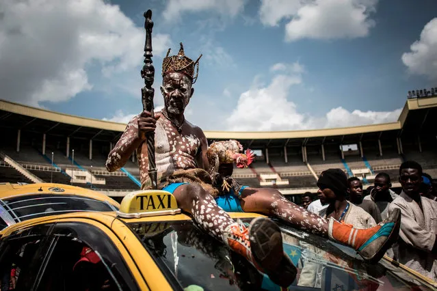 A Congolese wrestler's fetisheur sits on top of a car as he arrives to the Stade De Martyrs for a sports exhibition day on January 8, 2019 in Kinshasa. (Photo by John Wessels/AFP Photo)