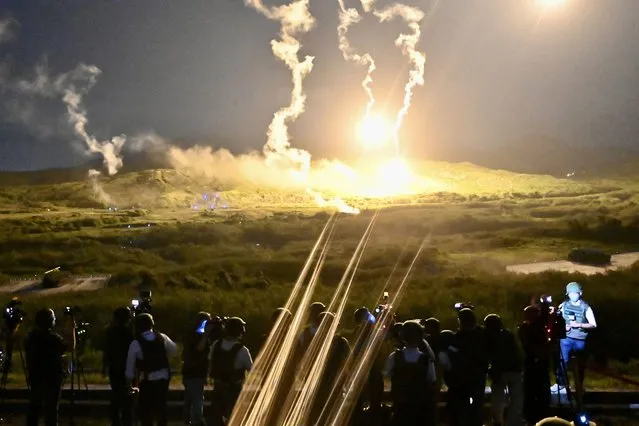 Members of the media (foreground) report as flares illuminate a mountainside during a live-fire exercises of Taiwan's Southern armoured brigade in Pingtung county, southern Taiwan, on September 6, 2022. (Photo by Sam Yeh/AFP Photo)