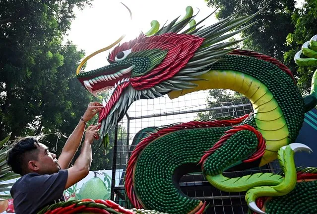 A worker arranges chili peppers on a dragon decoration made with vegetable during the Hanoi Fruit Festival at Thong Nhat park in Hanoi on November 8, 2023. (Photo by Nhac Nguyen/AFP Photo)
