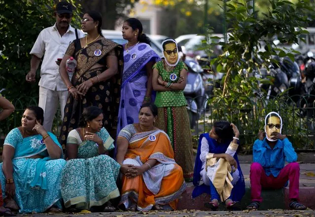 Children wear masks of Bhim Rao Ambedkar, as they wait with their family outside the Indian Parliament, before going in to pay tribute to Ambedkar on his birth anniversary in New Delhi, India, Tuesday, April 14, 2015. Ambedkar, an untouchable, or Dalit, and a prominent Indian freedom fighter, was the chief architect of the Indian Constitution, which outlawed discrimination based on caste. (Photo by Saurabh Das/AP Photo)
