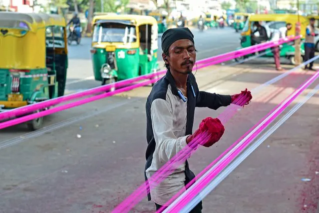 A man applies coats of glass powder to kite strings ahead of the Hindu festival “Uttarayan” in Ahmedabad on December 21, 2023. (Photo by Sam Panthaky/AFP Photo)