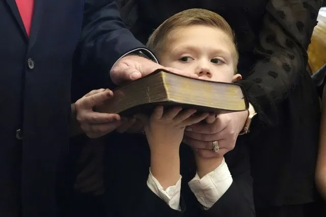 Casper Rhodes, 6, struggles to hold up the family's Bible as his father state Sen. Brian Rhodes, R-Pelahatchie, places his hand on the book and recites the oath of office during the swearing in ceremony in the Senate Chamber at the Mississippi State Capitol in Jackson, Miss., Tuesday, January 2, 2024. Both chambers of lawmakers were sworn into the new four-year term that began at noon Tuesday. (Photo by Rogelio V. Solis/AP Photo)