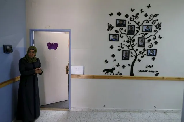 A teacher stands next to a tree design featuring pictures of distinctive blind and visually impaired Palestinian students at a school where they are taught English through song and music, in the West Bank city of Hebron March 2, 2016. (Photo by Ammar Awad/Reuters)