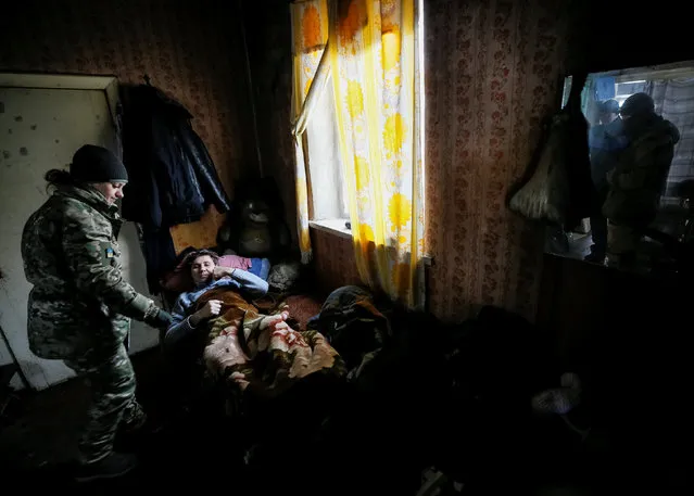 A military doctor helps local resident in the government-held industrial town of Avdiyivka, Ukraine, February 2, 2017. (Photo by Gleb Garanich/Reuters)