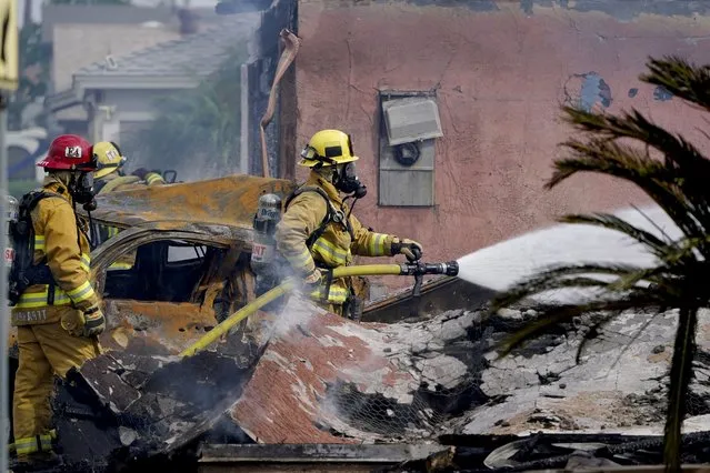 Fire crews work the scene of a small plane crash, Monday, October 11, 2021, in Santee, Calif. At least two people were killed and two others were injured when the plane crashed into a suburban Southern California neighborhood, setting two homes ablaze, authorities said. (Photo by Gregory Bull/AP Photo)