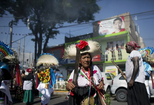 A woman dressed as a Zacapoaxtla Indian holds a machete as she dances before the start of a reenactment of the battle of Puebla, between Zacapoaxtla Indians and the French army, during Cinco de Mayo celebrations in Mexico City, Tuesday, May 5, 2015. (Photo by Rebecca Blackwell/AP Photo)