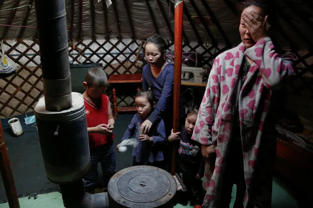The wife and children of Setevdorj Myagmartsogt gather around their new coal burning stove while talking to reporters in their tent-like ger home in Ulaanbaatar, Mongolia January 29, 2017. Setevdorj Myagmartsogt, a part time worker at coal packing shop, lives with his wife, four kids and two relatives in their ger home near a coal depot not far from the city centre. (Photo by B. Rentsendorj/Reuters)