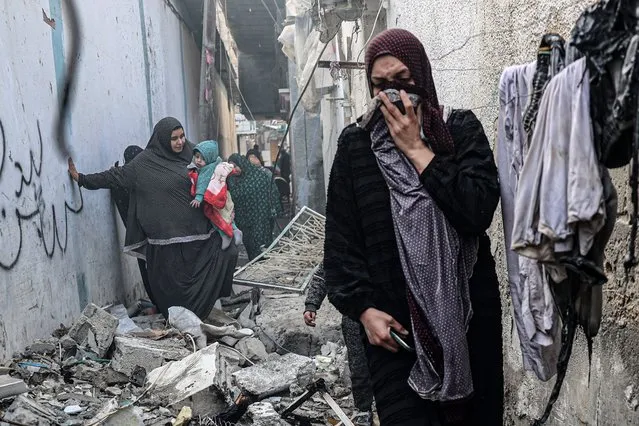 People find their way through a rubble-covered alley, following overnight Israeli bombardment in Rafah in the southern Gaza Strip on February 25, 2024, amid continuing battles between Israel and the Palestinian militant group Hamas. (Photo by Said Khatib/AFP Photo)