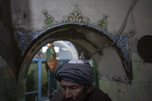 A Hazara man enters a Shiite shrine in Kabul, Afghanistan, Friday, November 5, 2021. A strange, new relationship is developing in Afghanistan following the takeover by the Taliban three months ago. The Taliban, Sunni hard-liners who for decades targeted the Hazaras as heretics, are now their only protection against a more brutal enemy: the Islamic State group. (Photo by Bram Janssen/AP Photo)