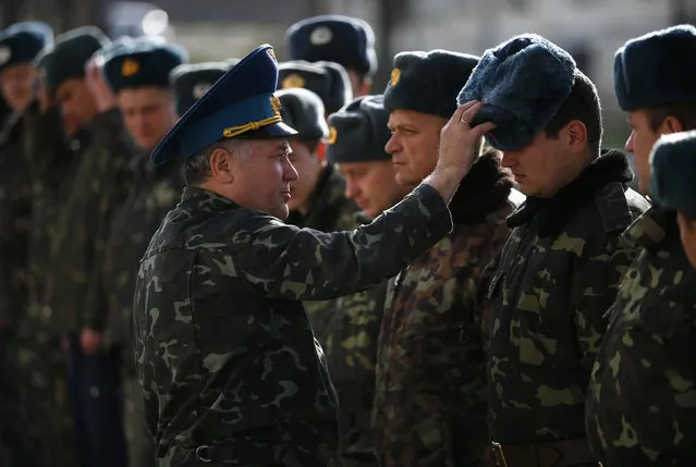 Viktor Kukharenko, chief of staff of a base in the Crimean village of Belbek, adjusts the hat of a soldier in the base, near Simferopol March 6, 2014. (Photo by Thomas Peter/Reuters)