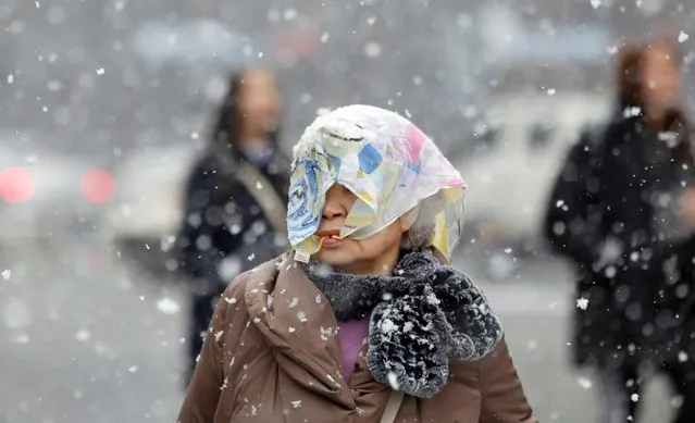 A woman covers her head with a scarf against heavy snow in Seoul, South Korea, February 16, 2016. (Photo by Lee Jin-man/AP Photo)
