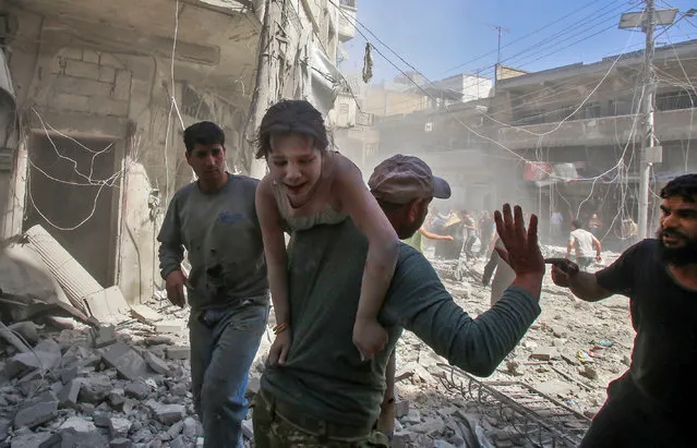 A man evacuates a young bombing casualty after a reported air strike by regime forces and their allies in the jihadist-held Syrian town of Maaret Al-Noman in the southern Idlib province, on May 26, 2019. Regime air strikes killed  12 civilians including four at a market today in a jihadist bastion in northwest Syria, a war monitor said. (Photo by Abdulaziz Ketaz/AFP Photo)