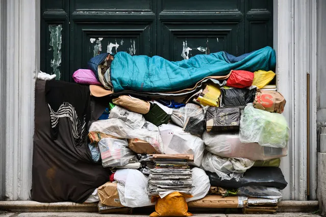 A homeless man sleeps on a pile of plastic bags and newspapers under a porch on April 7, 2019 in Rome, Italy. (Photo by Vincenzo Pinto/AFP Photo)