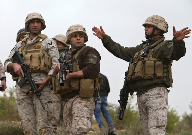 A Lebanese army officer from a commando unit, right, gives orders to his soldiers after they blew up a bomb-packed parked car in a field outside the village of Fakiha, near the Lebanese and Syria border, in northeast Lebanon, Monday, March 17, 2014. (Photo by Hussein Malla/AP Photo)