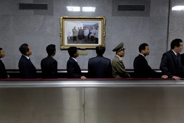 On a moving pavement, men pass a photo of the Dear Leaders in Kumsusan Palace after visiting their bodies which lie, “lit de parade,” or in repose for viewing. Pyongyang is said to have 2.5 million inhabitants. Only the upper caste, known as the core class, is allowed to stay in the capital. In reality, no one outside North Korea knows the exact population. (Photo by Peter Hove Olesen)