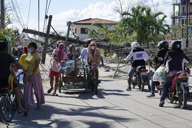Residents pass by toppled electrical posts due to Typhoon Rai in Cebu province, central Philippines on Monday December 20, 2021. The death toll in the strongest typhoon to batter the Philippines this year continues to rise and the governor of an island province especially hard-hit by Typhoon Rai said there may be even greater devastation that has yet to be reported. (Photo by Jay Labra/AP Photo)