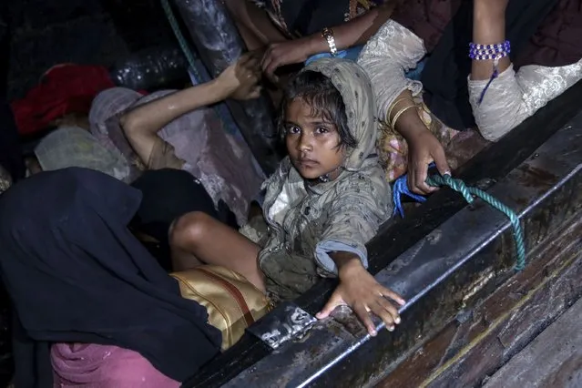 A young girl sits in a wooden boat carrying Rohingya refugees as it arrives at Krueng Geukueh Port in North Aceh, Indonesia, early Friday, December 31, 2021. A group of 120 Rohingya Muslims disembarked from a boat that had drifted for days off Indonesia's northernmost province of Aceh and was towed by a navy ship into port, officials said Friday. (Photo by Zik Maulana/AP Photo)