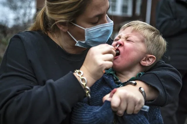 Sarah Glick, helps her son Harrison, 3, by swabbing his nose while getting tested for COVID-19 at the Curative testing van parked off Wightman Street in the Squirrel Hill neighborhood of Pittsburgh, Tuesday, December 28, 2021. Ms. Glick said they were getting tested as a precaution before visiting her mother. (Photo by Alexandra Wimley/Pittsburgh Post-Gazette via AP Photo)