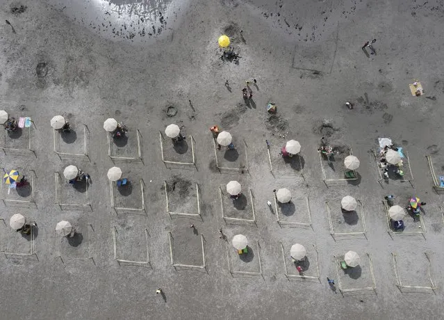 People rest in their separate areas on the beach amid the COVID-19 pandemic at Los Yuyos beach in Lima, Peru, Thursday, December 16, 2021. (Photo by Martin Mejia/AP Photo)