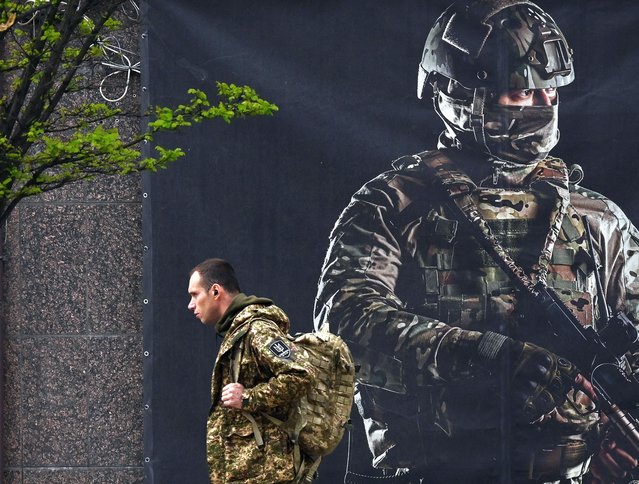 A Ukrainian serviceman walks past a recruiting poster in Kyiv on April 23, 2024, amid the Russian invasion of Ukraine. (Photo by Sergei Supinsky/AFP Photo)