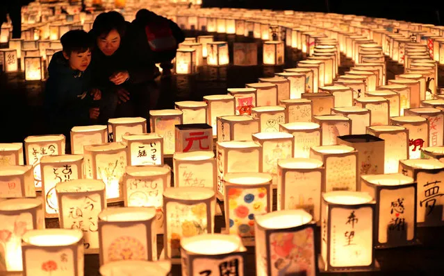 A family looks at paper lanterns during a memorial event to mourn victims of the March 11, 2011 earthquake and tsunami disaster, in Natori, Miyagi prefecture, Japan, in this photo taken by Kyodo March 11, 2017, to mark the six-year anniversary of the disaster that killed thousands and set off a nuclear crisis. (Photo by Reuters/Kyodo News)