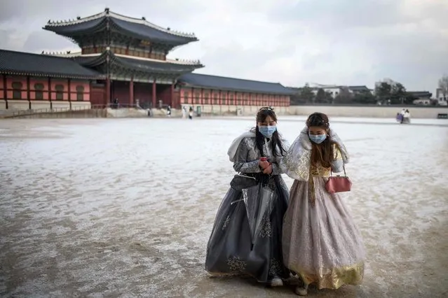 Visitors wear traditional hanbok dress as they walk on the grounds of the Gyeongbokgung Palace after a snowfall in Seoul on January 17, 2022. (Photo by Anthony Wallace/AFP Photo)