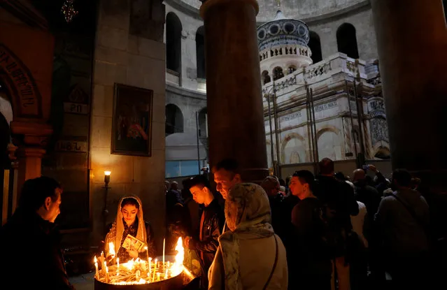 Worshippers light candles as the newly restored Edicule, the ancient structure housing the tomb, which according to Christian belief is where Jesus's body was anointed and buried, is seen in the background at the Church of the Holy Sepulchre in Jerusalem's Old City March 20, 2017. (Photo by Ronen Zvulun/Reuters)