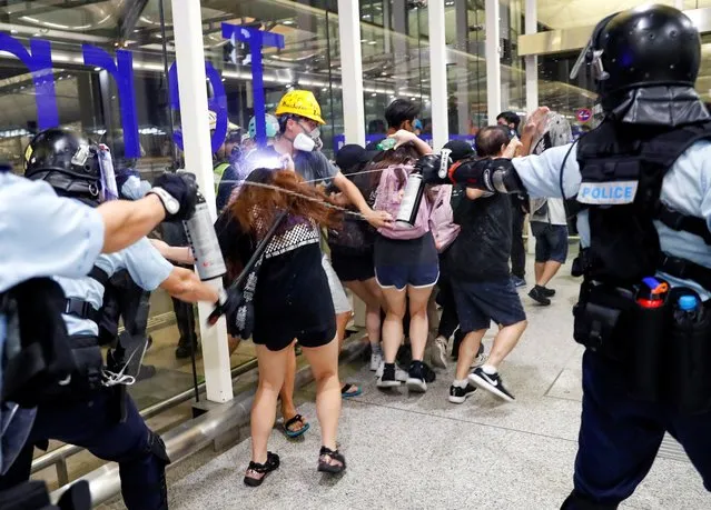 Riot police use pepper spray to disperse anti-extradition bill protesters during a mass demonstration at the Hong Kong international airport, August 13, 2019. (Photo by Tyrone Siu/Reuters)