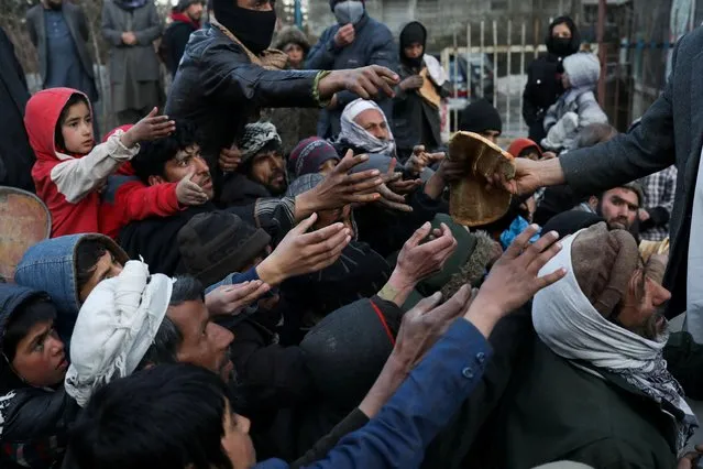 People reach out to receive bread in Kabul, Afghanistan, January 31, 2022. (Photo by Ali Khara/Reuters)