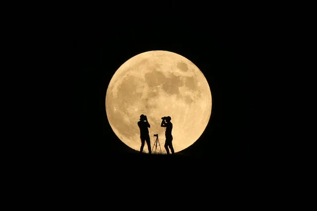 The full moon rises behind photographers' silhouettes in Van, Turkey on July 16, 2019. (Photo by Ozkan Bilgin/Anadolu Agency/Getty Images)