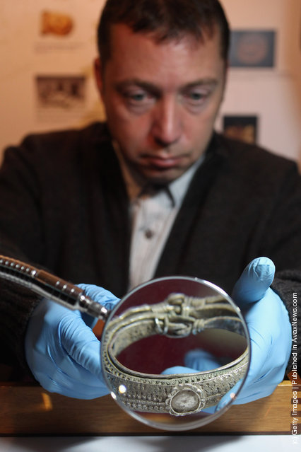 An employee of the British Museum examines a silver arm-rings dating from 900 AD which are part of the Silverdale Viking Hoard