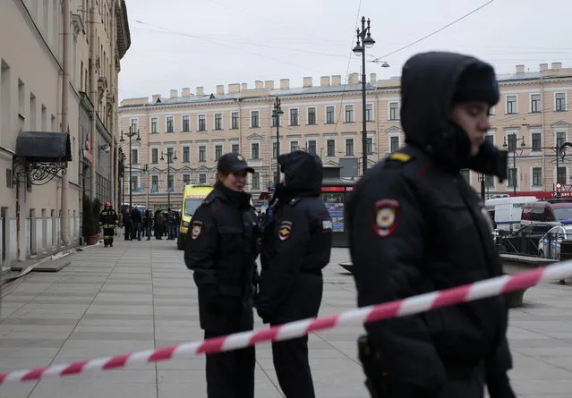 Russian police officers stand guard in a street after a explosion in St. Petersburg's subway, Russia, Monday, April 3, 2017. (Photo by Evgenii Kurskov/AP Photo)