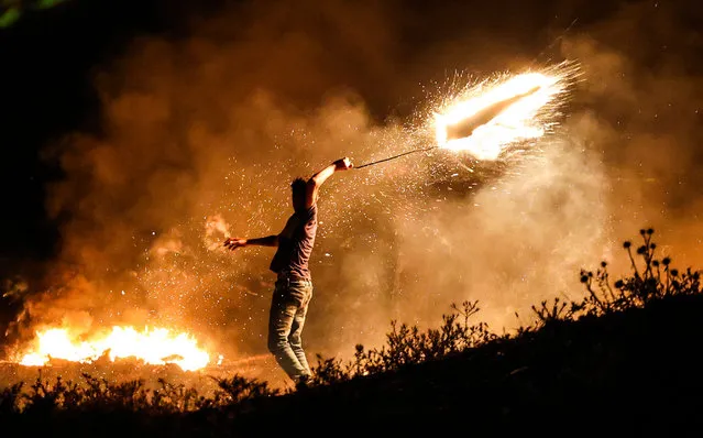 A Palestinian protester throws a burning projectile towards Israeli forces during a demonstration east of Gaza City by the border with Israel, on June 15, 2021, to protest the Israeli ultranationalist March of the Flags in Jerusalem's Old City which celebrates the anniversary of Israel's 1967 occupation of Jerusalem's eastern sector. (Photo by Mahmud Hams/AFP Photo)